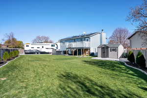 Back of property featuring a fenced backyard, a storage shed, a patio, and a wooden deck