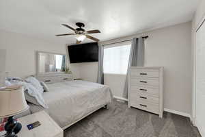 Carpeted bedroom featuring multiple windows and a ceiling fan