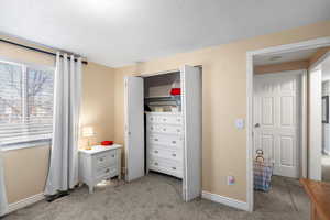 Bedroom with light carpet and a closet