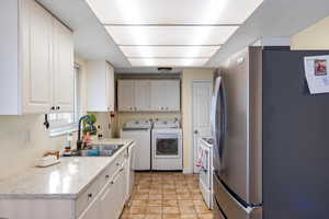 Kitchen with white appliances, white cabinetry, and washer and clothes dryer