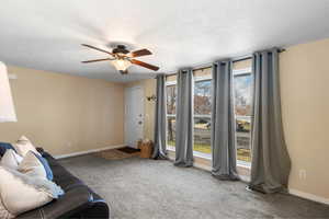 Unfurnished living room with light carpet, ceiling fan, and a textured ceiling