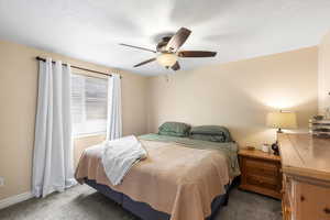 Bedroom with carpet, a ceiling fan, and a textured ceiling