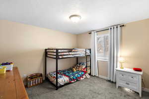 Carpeted bedroom with a textured ceiling and baseboards