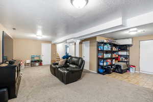 Living area featuring a textured ceiling, light carpet, and stairway