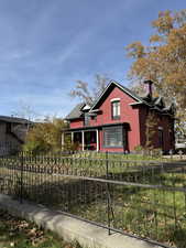 View of front of home with a fenced front yard, a chimney, covered porch, and brick siding