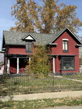 View of front of house with brick siding, a fenced front yard, and a shingled roof