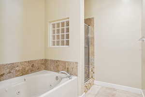 Bathroom featuring a jetted tub, a stall shower, and tile patterned floors