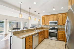 Kitchen featuring a kitchen bar, stainless steel appliances, tasteful backsplash, decorative light fixtures, and recessed lighting