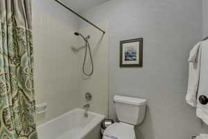 Bathroom with shower / tub combo and toilet, tile flooring