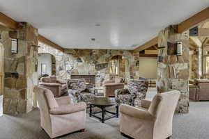Common area with arched walkways, beam ceiling, and a fireplace