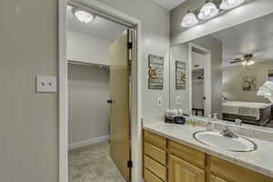 Bathroom featuring vanity, ensuite bath, a spacious walk-in closet, brand new carpet, and ceiling fan