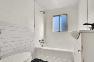 Full bath featuring tile walls, vanity, and tub / shower combination