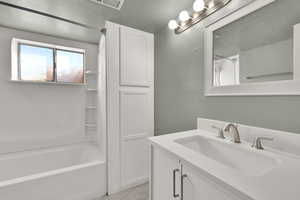Full bath featuring vanity, bathing tub / shower combination, and a textured wall