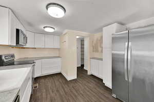 Kitchen featuring stainless steel appliances, white cabinetry, and dark wood finished floors
