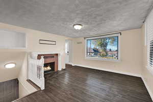 Unfurnished living room featuring a fireplace and dark wood-style flooring