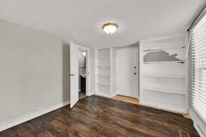 Unfurnished bedroom with baseboards and dark wood-style floors