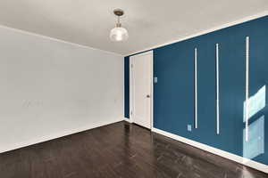 Spare room featuring dark wood-style floors and ornamental molding