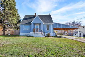 View of front facade featuring a shingled roof, a chimney, concrete driveway, and a carport