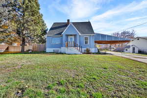 View of front of home featuring a chimney, a shingled roof, driveway, and an attached carport
