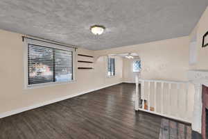 Unfurnished living room with plenty of natural light, dark wood-style floors, arched walkways, and a textured ceiling