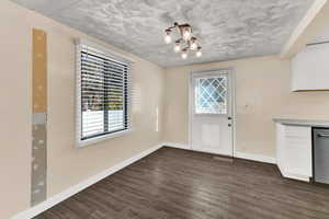 Unfurnished dining area featuring dark wood finished floors and a chandelier