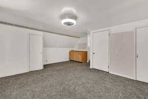 Additional living space featuring light carpet and vaulted ceiling