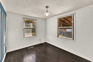 Spare room featuring dark wood-type flooring and a textured ceiling