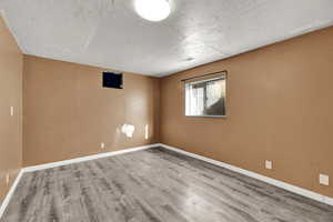 Empty room featuring a textured ceiling and light wood-type flooring