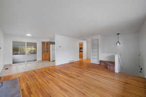 Unfurnished living room featuring light wood-style floors and built in shelves