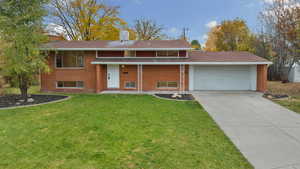 View of front facade featuring a porch, a front yard, a chimney, and brick siding