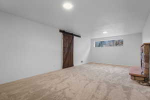 Unfurnished living room with a barn door and light carpet