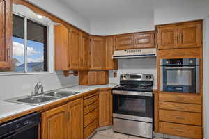 Kitchen with brown cabinets, appliances with stainless steel finishes, light countertops, and light tile patterned flooring