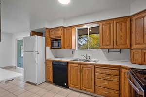 Kitchen with black appliances, light countertops, brown cabinets, and healthy amount of natural light