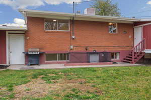 Back of property with a patio, brick siding, a chimney, and a yard