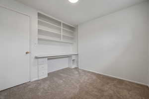 Unfurnished office featuring light colored carpet and built in desk