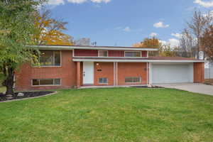 Raised ranch with a front lawn, brick siding, concrete driveway, an attached garage, and a porch