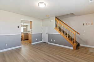 Unfurnished living room with light wood-style floors, a chandelier, and stairs