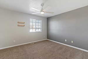 Spare room with carpet flooring, a ceiling fan, and a textured ceiling
