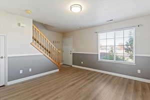 Unfurnished living room featuring stairs and light wood finished floors