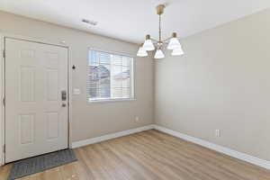 Entryway with light wood finished floors and a chandelier