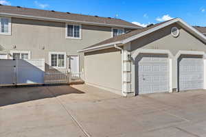 Rear view of property with stucco siding, a gate, driveway, and an attached garage