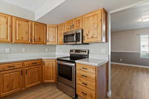 Kitchen with appliances with stainless steel finishes, light wood-style floors, and a textured ceiling
