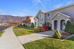 Traditional-style house with a front lawn, stucco siding, a residential view, and a mountain view