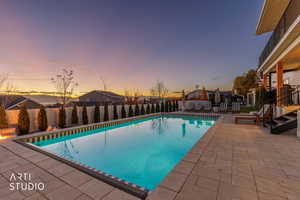 Pool at dusk featuring a patio and a fenced backyard