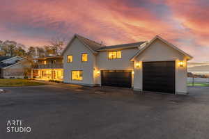 View of front facade featuring asphalt driveway, stucco siding, a balcony, and an attached garage