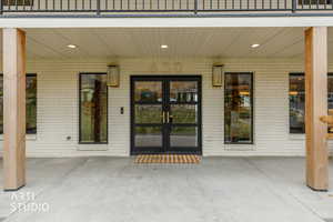Property entrance featuring brick siding, a patio, and french doors