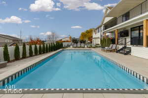 Community pool featuring a patio, a balcony, and a residential view