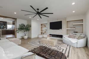Living area featuring light wood-style flooring, a fireplace, recessed lighting, built in shelves, and ceiling fan