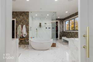 Ensuite bathroom featuring a walk in closet, a freestanding bath, recessed lighting, and a marble finish shower