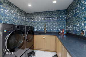 Washroom with wallpapered walls, cabinet space, recessed lighting, and washer and dryer